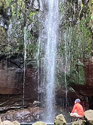 Trainering hockend vor einem Wasserfall
